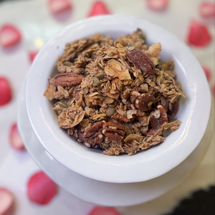 White container filled with granola on a surface with pink petals