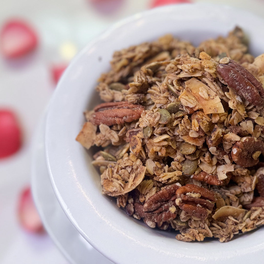 White container filled with granola on a surface with pink petals